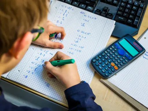 Niño resolviendo problemas matemáticos, practicando la tabla del 7. Una calculadora y un teclado están cerca.